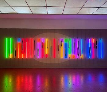 Román Vitali. "La Espera" ( L’attesa) Año: 2017-24.  Luz de neón. Transformadores y secuenciadores. Tejido con cuentas de acrílico facetadas y tanza sobre estructuras de madera revestidas en oro a la hoja. Pintura y dibujo sobre pared. Dimensiones: 300 x 920 x 20 cm.